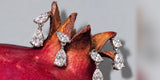Pear-shaped crystal drop earrings resting on top of a pomegranate