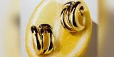 Chunky gold Oomiay earrings resting on a cut lemon