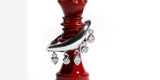 A silver Oomiay ring with crystal drops resting on a red chess queen