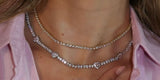 Two tennis necklaces layered at the base of the neck and just below it