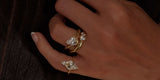 A hand wearing Oomiay gold rings, including a kite-shaped crystal ring on the pinky