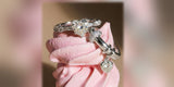 Sterling silver rings with a heart crystal and a heart charm stacked on a pink meringue