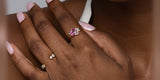 A hand resting at the collarbone, wearing Oomiay rings on two fingers