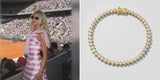 A woman in a pink striped dress at a tennis stadium, beside the Gold Spike Tennis Bracelet