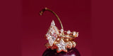 A stack of gold Oomiay rings with a kite-shaped crystal and a crystal star, resting on a dark plum