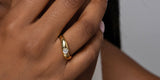 A hand wearing the Oomiay Crush ring, a bezel-set heart on a curved gold band