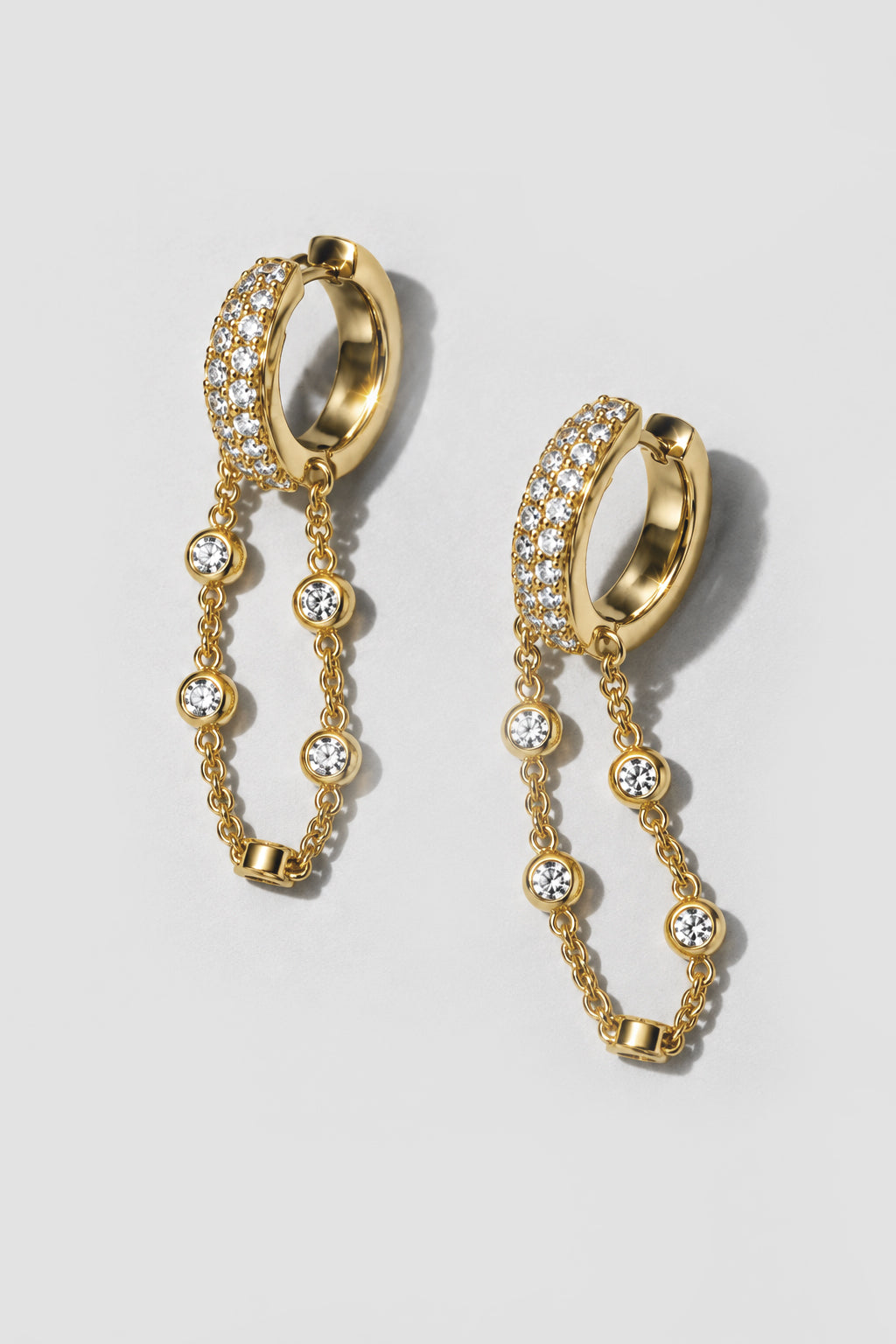 Gold Eclipse Earrings. Pavé huggie of mixed-size crystals with a draped bezel crystal chain