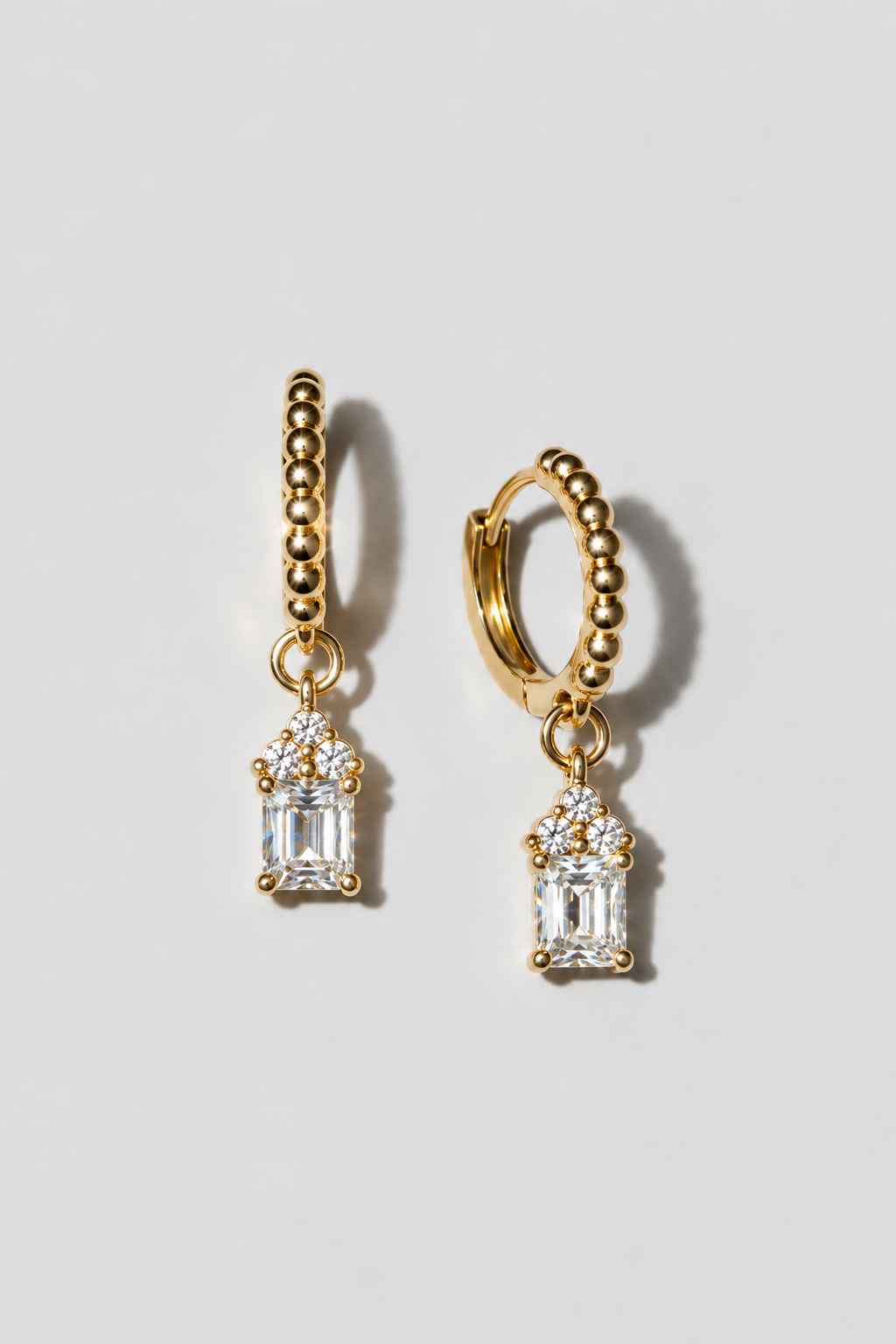 Gold Emerald Cut Huggies. Beaded huggie with a 5x7mm emerald cut white crystal charm under a three-crystal cap
