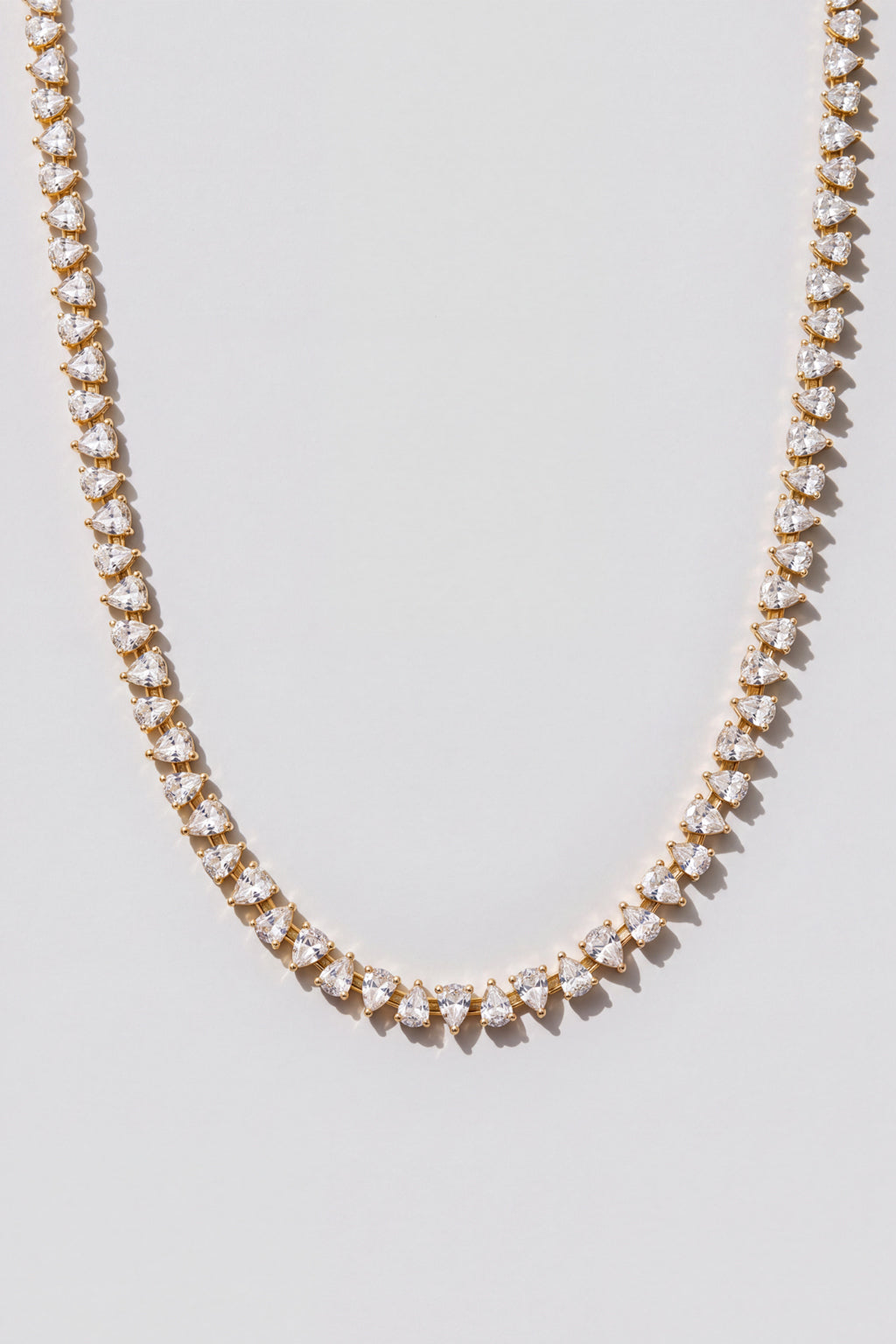 Gold Reverse Pear Cut Tennis Necklace. Hand-linked tennis necklace of 5x7mm reverse pear cut white crystals, spaced with a gap between each stone so it lays flat
